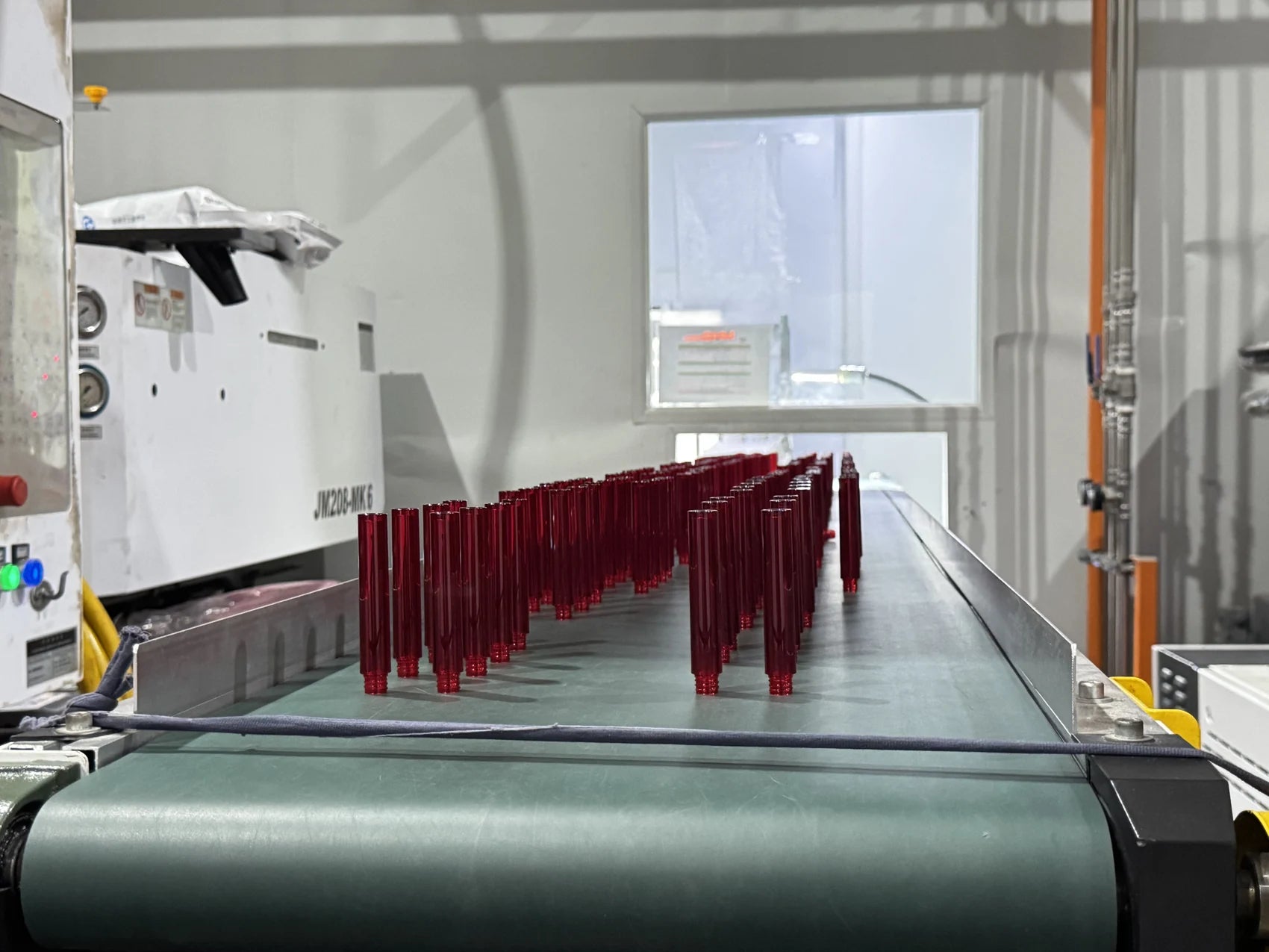 Burgundy cosmetic packaging components on a production conveyor